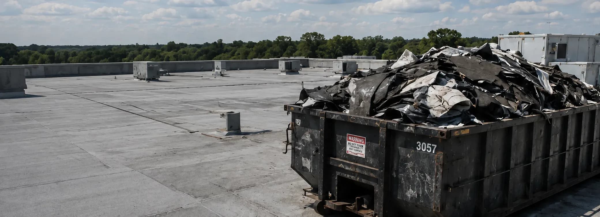 Roof tear-off underway beside a commercial building